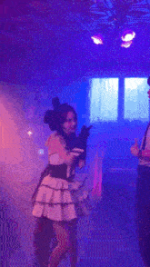 a girl in a pink and black dress is dancing in a dark room .