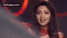 a woman in a red dress is smiling in front of a red light .