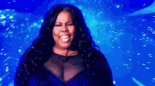 a woman in a blue dress is singing on a stage .