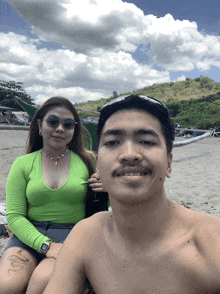 a man and a woman are posing for a selfie on the beach