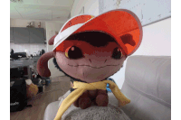 a stuffed animal wearing a hat and scarf sits on a couch in front of a domino 's bag