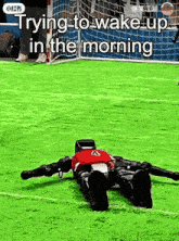 a robot is laying on a soccer field with the words trying to wake up in the morning below it