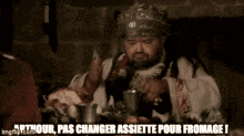 a man with a beard is sitting at a table and says arthour pas changer assiette pour fromage !