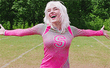 a woman in a pink and green uniform with the letter s on it is standing on a field .