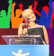 a woman is standing at a podium talking into a microphone