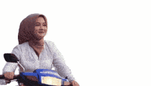 a woman wearing a hijab is riding a blue scooter with the words assalamu alaikum