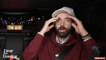 a man wearing a hat and glasses is sitting in a car with a sign that says on air