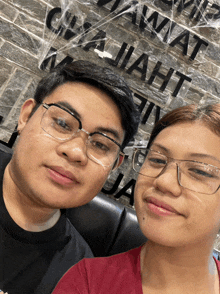 a man and a woman are posing for a picture in front of a brick wall that says ' ijaht '
