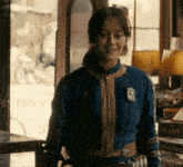 a woman wearing a blue jacket with a badge that says ' a ' on it is standing in front of a window