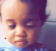 a close up of a baby 's face with a sad look on his face