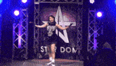 a woman is dancing in front of a sign that says star dom
