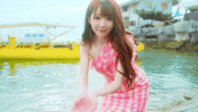 a girl in a pink dress is standing in the water