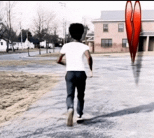 a man in a white shirt is walking down a street with a red heart in the background