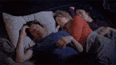 a man and two women are sleeping together in a bed .
