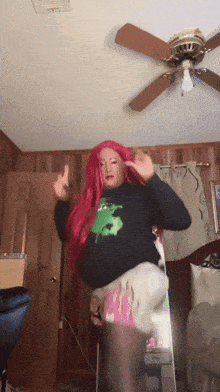 a woman with red hair is dancing in front of a ceiling fan in a bedroom