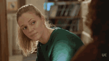 a woman in a green shirt is looking at another woman in a uc ad