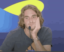 a man with a watch on his wrist is sitting in front of a microphone