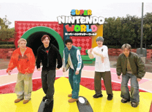 a group of young men are standing in front of a sign that says super nintendo world