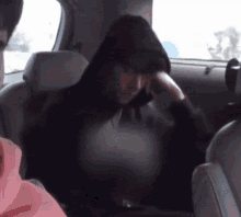 a man in a black hoodie is sitting in a car