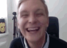 a man wearing headphones is laughing with his eyes closed while sitting in a chair .