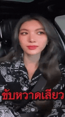 a woman in a black shirt is sitting in a car with a foreign language written on it