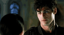 a man with a tattoo on his neck is looking at a woman in a room .