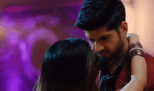 a man and a woman are dancing in a dark room with purple lights behind them .