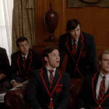 a boy in a school uniform holds his hand up