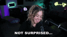 a woman wearing a cat ear headband is talking into a microphone and says not surprised