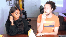 a man and a woman are sitting at a table and eating chips