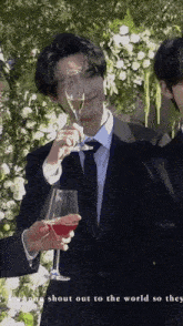 a man in a suit and tie is holding a glass of red wine