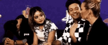 a man and a woman are sitting next to each other in front of a purple background .
