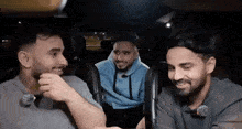 three men are sitting in the back seat of a car laughing .