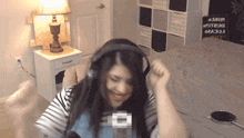 a woman wearing headphones is dancing in front of a microphone in a bedroom