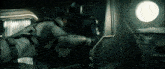 two men are fighting in a dark room with a round window in the background .