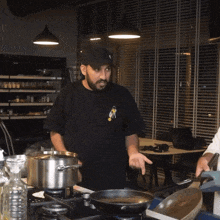 a man in a black shirt with the letter r on it is cooking