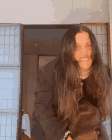 a woman with long dark hair is standing in a doorway smiling