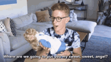 a man holding a doll with the words where are we going to put you my sweet sweet angel behind him