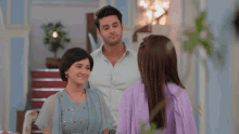 a man and two women are standing in a room