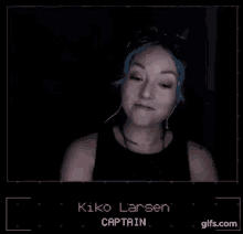 a woman with blue hair is wearing headphones and the name kiko larsen is on the screen behind her