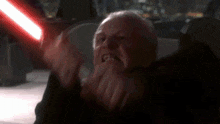 an old man with a beard is holding a red light saber