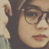 a close up of a person wearing glasses and a hijab .