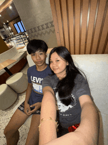 a boy wearing a levi t-shirt sits next to a girl