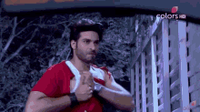 a man in a red shirt and white shirt is standing in front of a building .