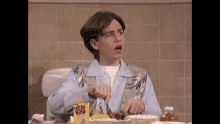 a young man in a blue shirt is sitting at a table eating a meal .