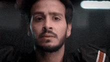 a close up of a man 's face with a beard and earrings .