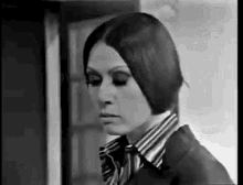 a black and white photo of a woman in a striped shirt and jacket .