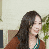 a woman with long black hair is smiling and wearing a sweater