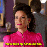 a woman in a pink shirt says you 're tying my hands but fine