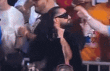 a man wearing sunglasses is being greeted by a woman in a crowd .